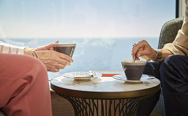 Two people enjoying coffee in the Britannia Lounge aboard Spirit of Adventure