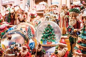 A variety of Christmas ornaments, including snow globes, on a Christmas Market stall